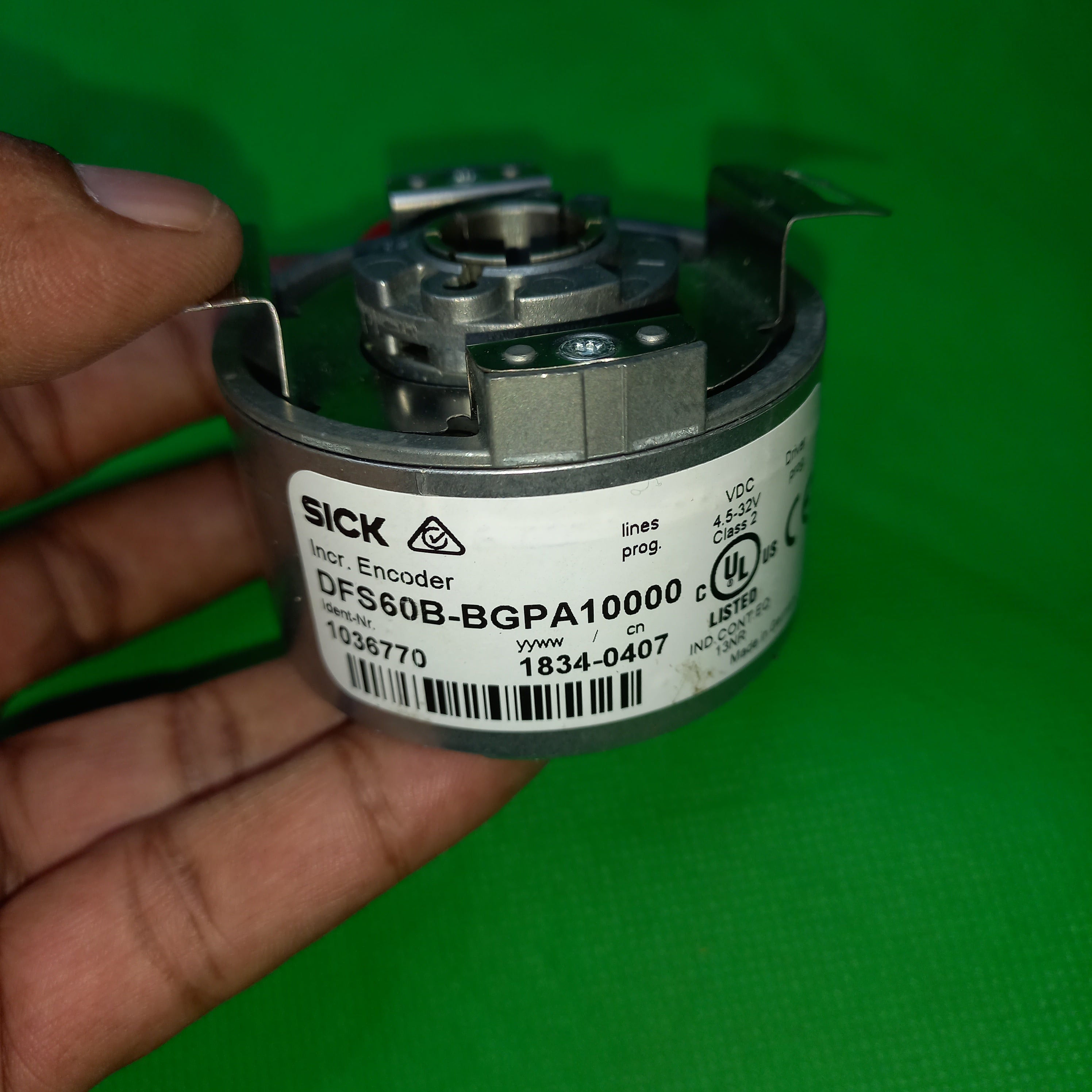 specification sticker view of SICK Hollow DFS60B-BGPA10000 Ident-Nr. 1036770 and frong flange and clamping ring can be seen
