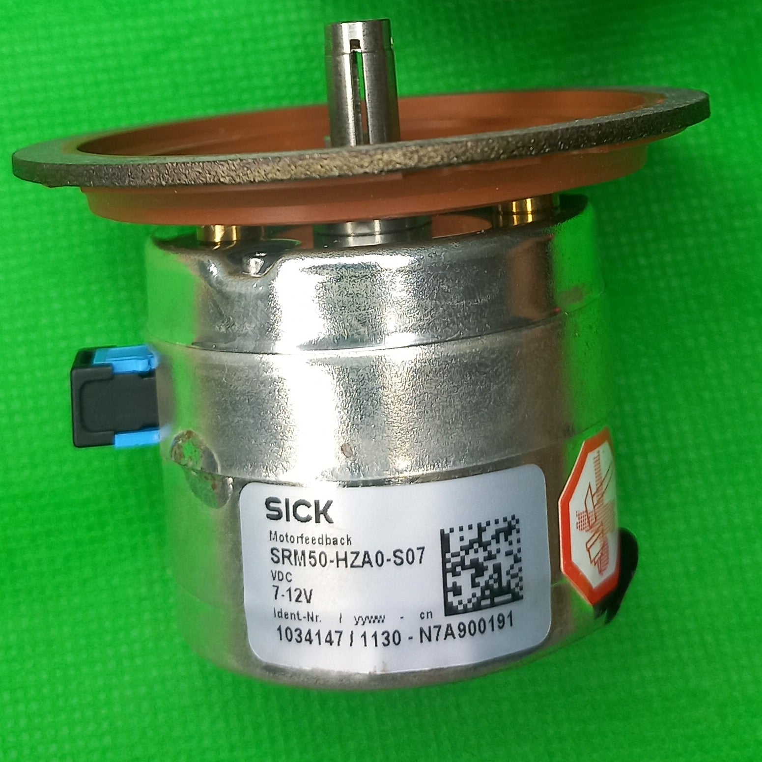 Two encoders SRM50-HZA0-S07 Part. Nr. 1034147 one showing face Flange and other is Specification sticker.