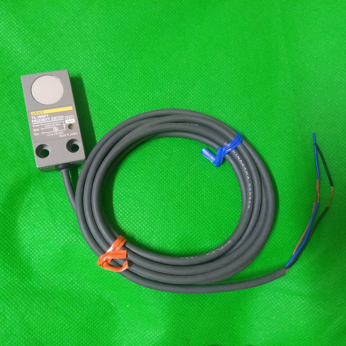 Complete view of TL-W5F1, Proximity Switch, PNP, NO, 12-24Vdc, made in Japan.  open wire ends and sensor visible